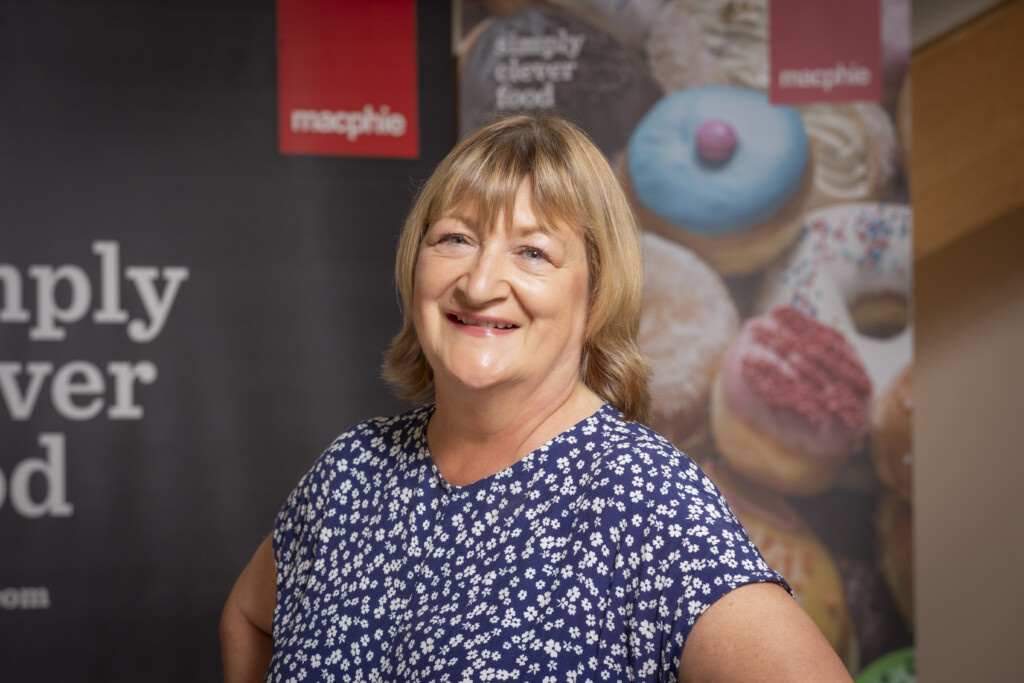Elaine Marshall with Macphie poster behind her to celebrate working with Machpie for 40 years 